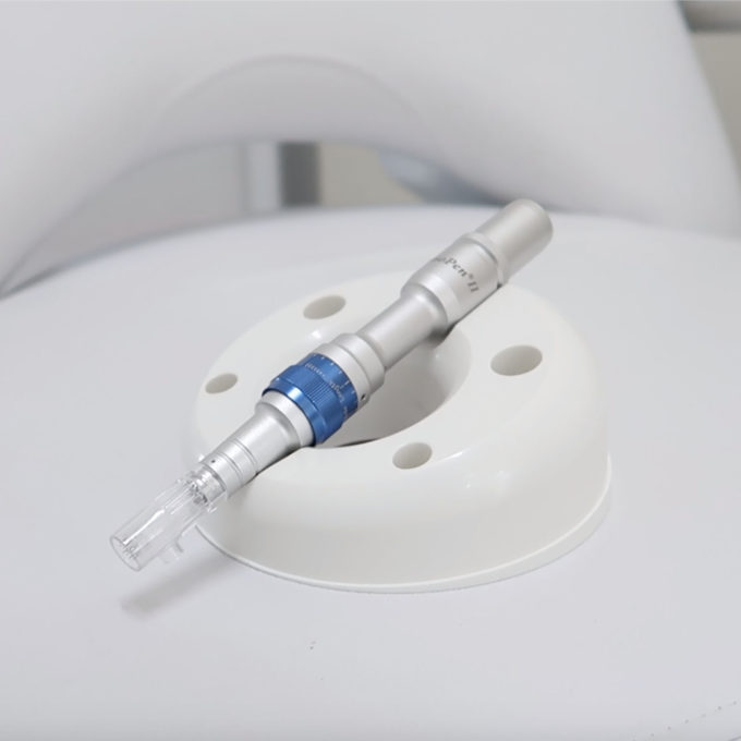 A blue and white device is sitting on top of a white chair, used for microneedling.