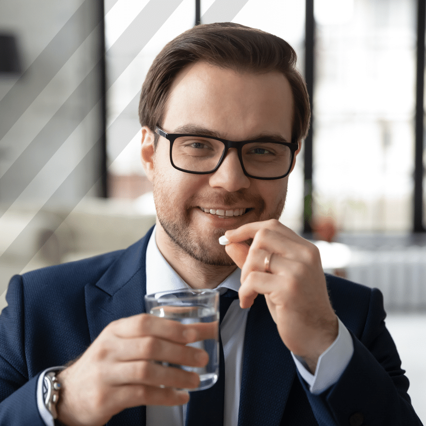 A man in glasses is holding a glass of water while wearing regenics.